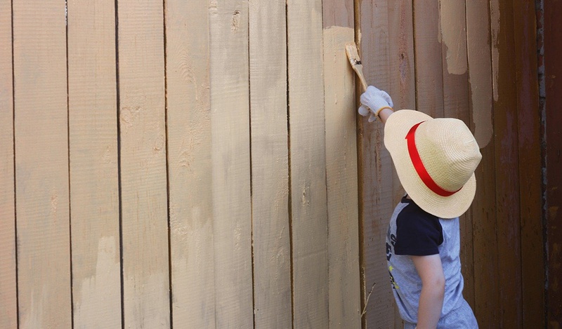 child painting the fence light brown