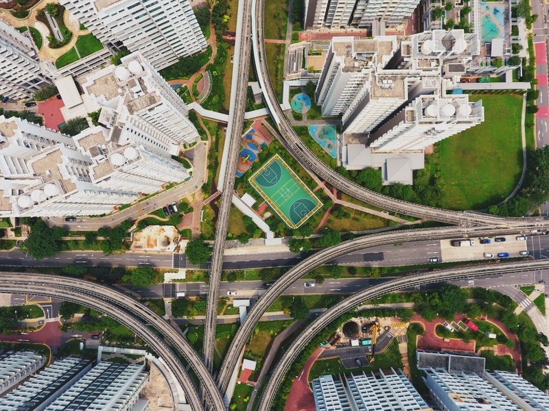 Aerial shot of an intersection with skyscrapers, parks, playgrounds and basketball pitch.